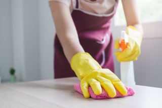someone cleaning a table with all-purpose cleaner and a cloth