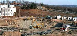 This is a picture of a cleanup with cement pipes at the site along with machinery, trucks and trailers.