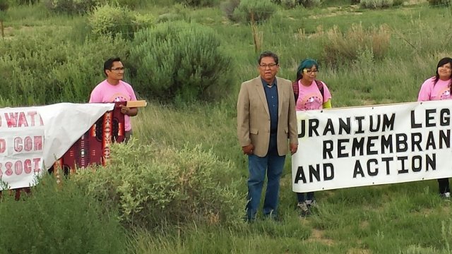 Four people holding banner: Uranium Legacy Remembrance and Action Day
