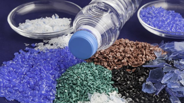 This is a photo of different colored recycled plastic granules. A plastic bottle is in the center of the shot.