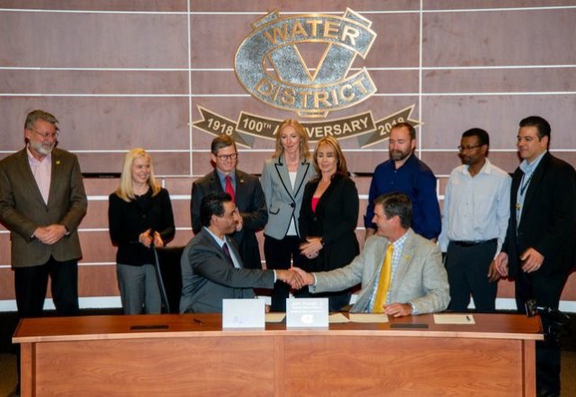 Tomás Torres (sitting, left) shaking hands with John Powell Jr., President of the Board, Coachella Valley Water District.