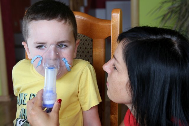 An adult helping a child use an inhaler