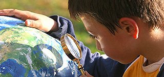 Boy looking at globe through magnifying glass [Search RAINE]