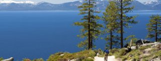 Bicyclist with view of Lake Tahoe's blue waters and snowcapped mountains.