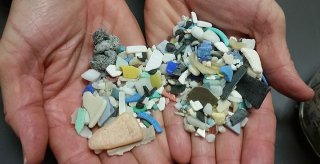 Pair of hands holding microplastics collected from a beach. Photo courtesy of National Ocean Service/NOAA.