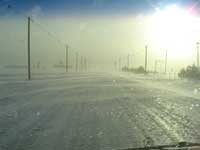 snow blowing across an icy road