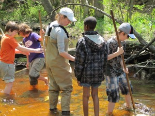 children and scientist in stream with dipnets