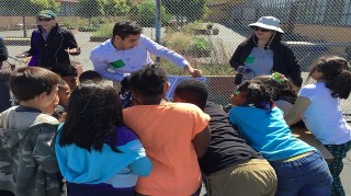 Three educators teaching a group of kids participatory science