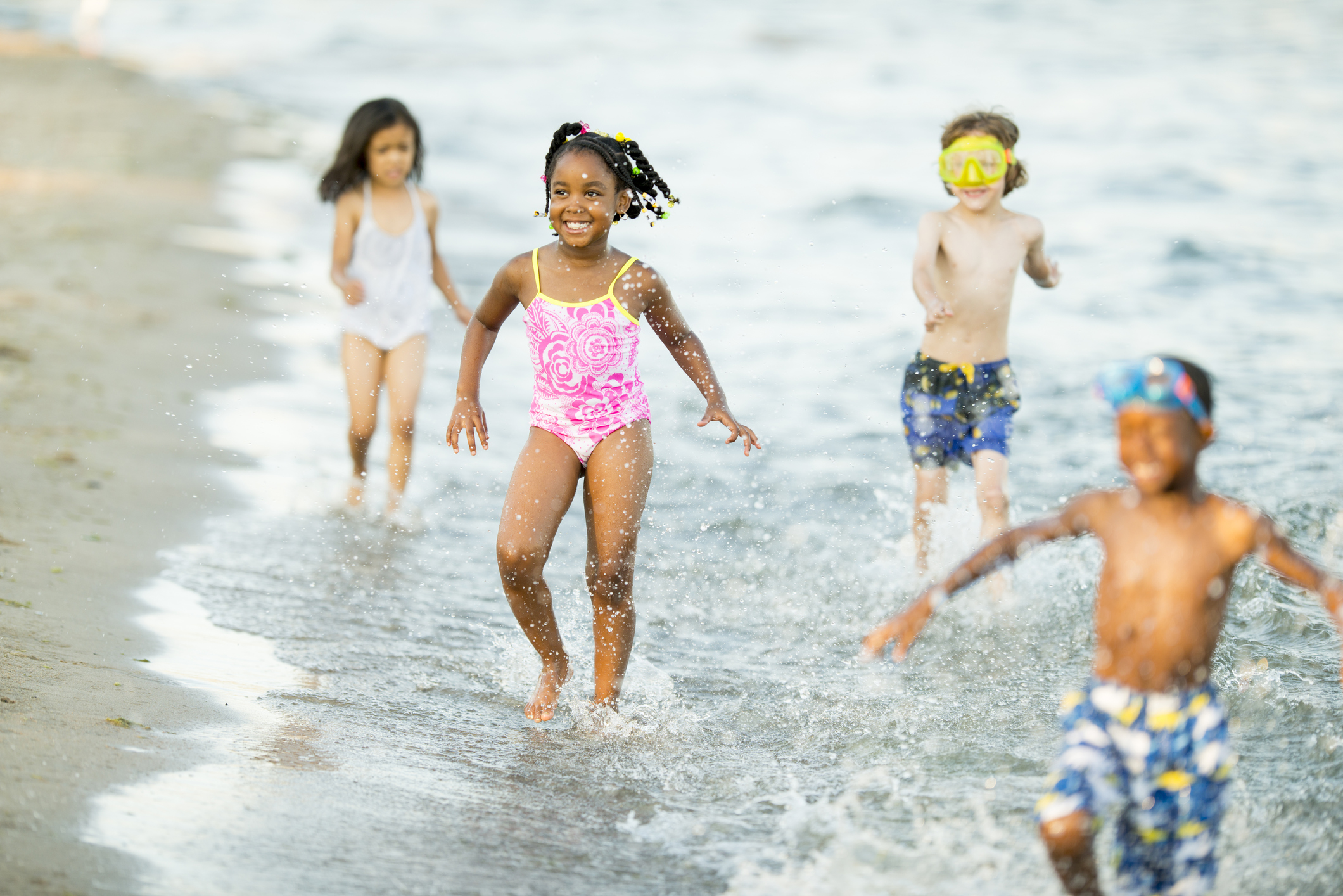 Photo of kids playing in water on a sandy beach