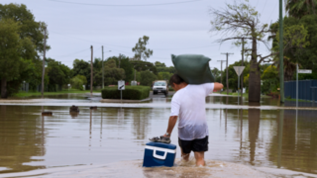 Photo: A man carrying belongings through a flooded street.