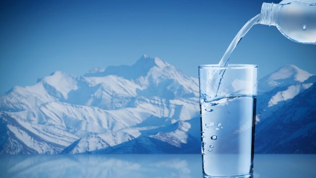 transparent filled water glass in front of a mountain range