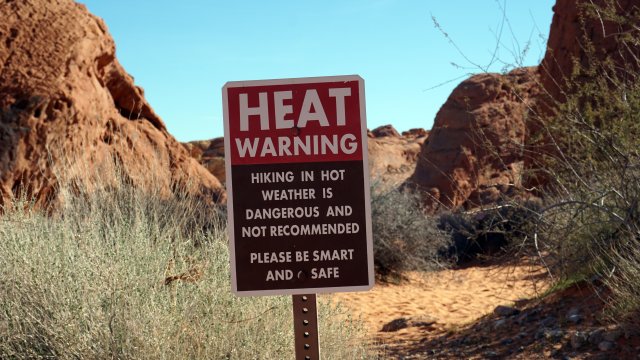 A heat warning sign beside a trail in the arid southwestern United States.