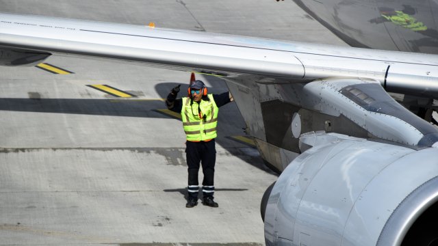 runway worker directs an airplane