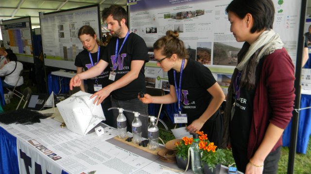 Four University of Washington students presenting their Fog Collection System to people outside of the image