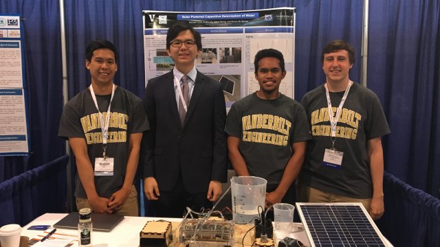 Four Vanderbilt students smiling and posing in front of their solar powered water deionization project