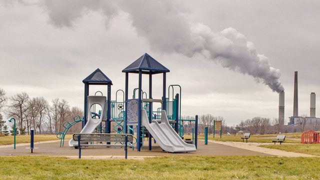 Playground with industrial smokes stacks in background