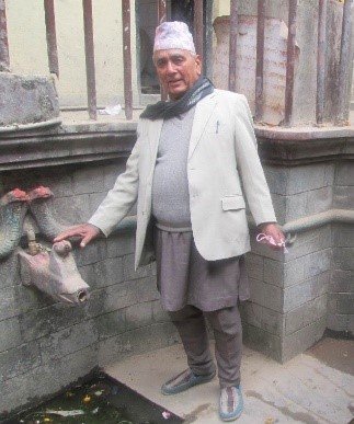 A citizen scientist (Mr. Tek Raj Ghimire, father of Santosh R. Ghimire) points towards a traditional stone-spouts (hiti) in Nepal. (Photo courtesy of Mr. Tek Raj Ghimire). 