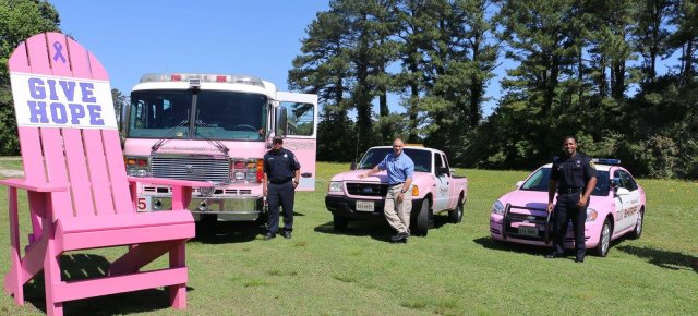 Photo of pink fire engines next to a large pink chair. 