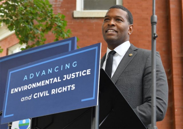 EPA Administrator Michael Regan speaking at a lectern with sign reading "Advancing Environmental Justice and Civil Rights"