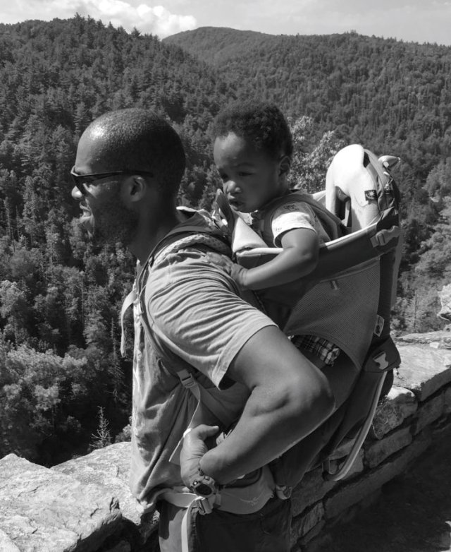man on hike holding his young son in a child carrying pack