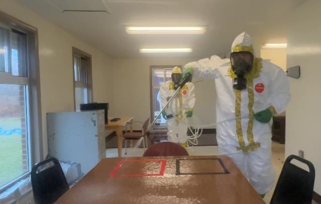 Spraying down a table with decontaminant.
