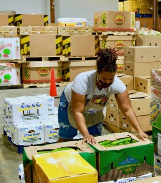 Image of woman sorting boxes of produce. 