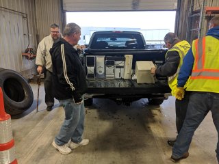 A group of men unloading recycled electronics out of a work truck. 