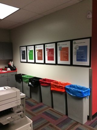 Photo of various brightly colored recycling bins in a hallway. 