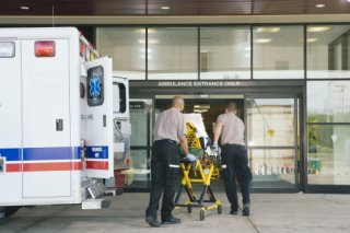 A team of paramedics wheels a patient on a gurney into a hospital emergency room.