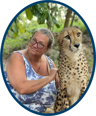 A woman wearing a tank top and glasses poses with a cheetah.