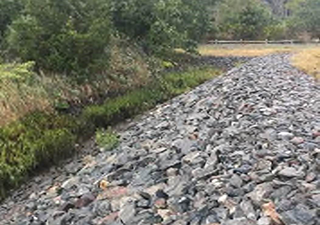 Photograph showing a stormwater drainage channel lined with mixed stones