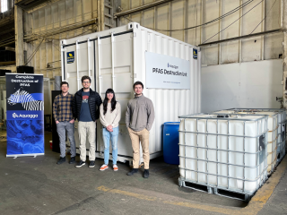 Four people stand in front of a large white unit