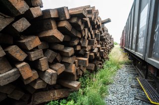 this is a photo of a pile of railroad ties next to a train 