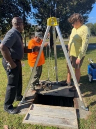 Researchers stand around open stormwater drain 