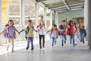 children laughing running through school hallway holding hands