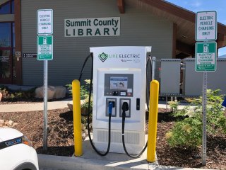 This image shows an electric vehicle charging station with two charger ports in front of a county library.