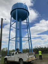 A compliance advisor visits a water storage tank with the system operator to discuss maintenance and other issues.