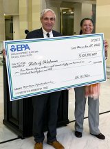 Two people holding a big check facsimile.