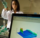 Image of an EPA scientist wearing gloves and using a pipette to analyze an environmental sample. There is a computer monitor in front displaying chemicals.