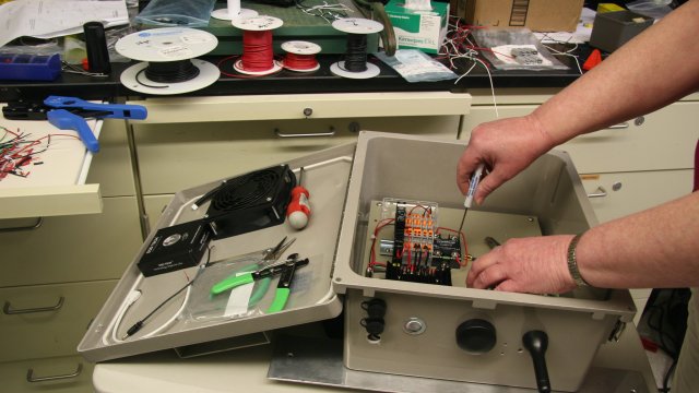 EPA researcher looks over internal components of sensor package, which includes a commercial low-cost air sensor, to measure fine particulate matter (PM2.5), black carbon, and meteorological conditions.