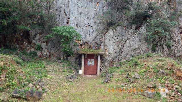 Red door at the base of a rock cliff.