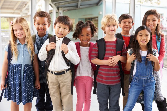 A group of children stand outside school