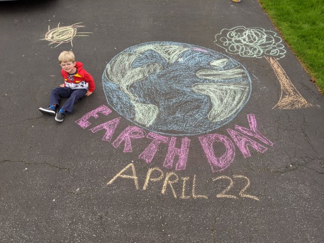 Little boy next to earth day drawing