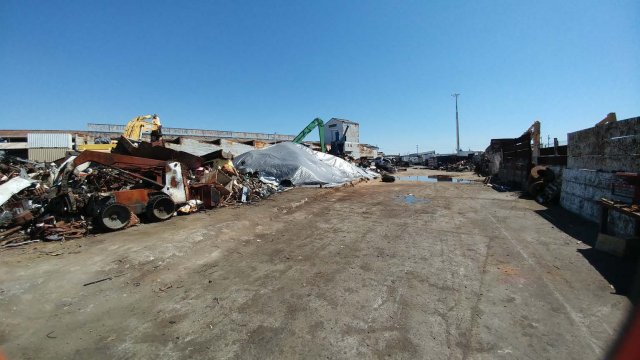 Central Metal site photograph showing piles of old equipment and plastic sheet covering soil.