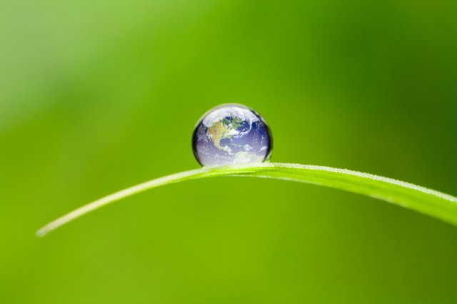 Image of Earth as a water droplet on a blade of grass.