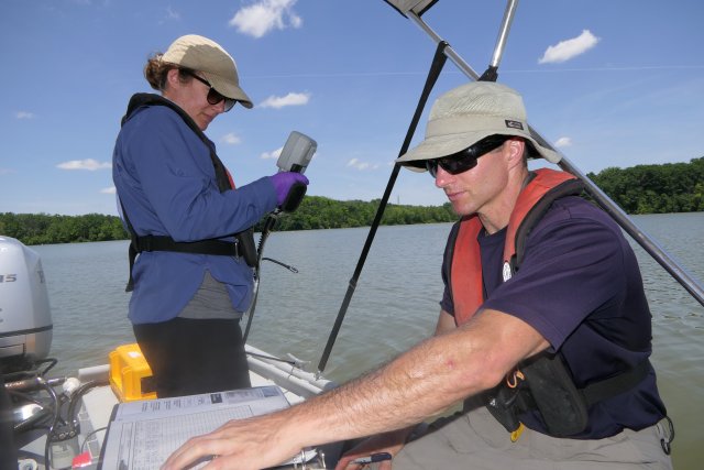 Sarah Waldo (left) takes measurements of the underwater conditions at Acton Lake and Jake Beaulieu (right) records the measurement results in their logbook.