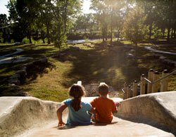 a girl and a boy about to go down a slide in a park