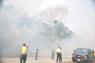 Photo showing researchers lifting a monitoring balloon to track smoke from a prescribed fire in Camp Lejeune, N.C.