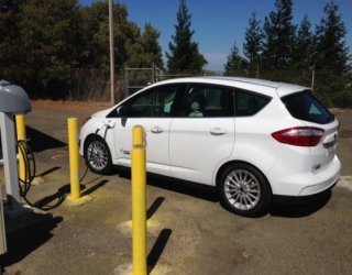 White, four-door EV connected to a charging station