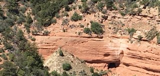 Desert cliff-face with mine entrance/opening and rock tailing pile visible